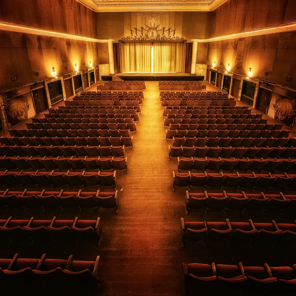 An empty vintage theatre, rows of seats and a softly lit centre aisle