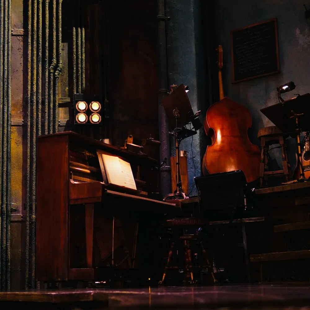 A piano and cello on a dimly lit stage before a performance